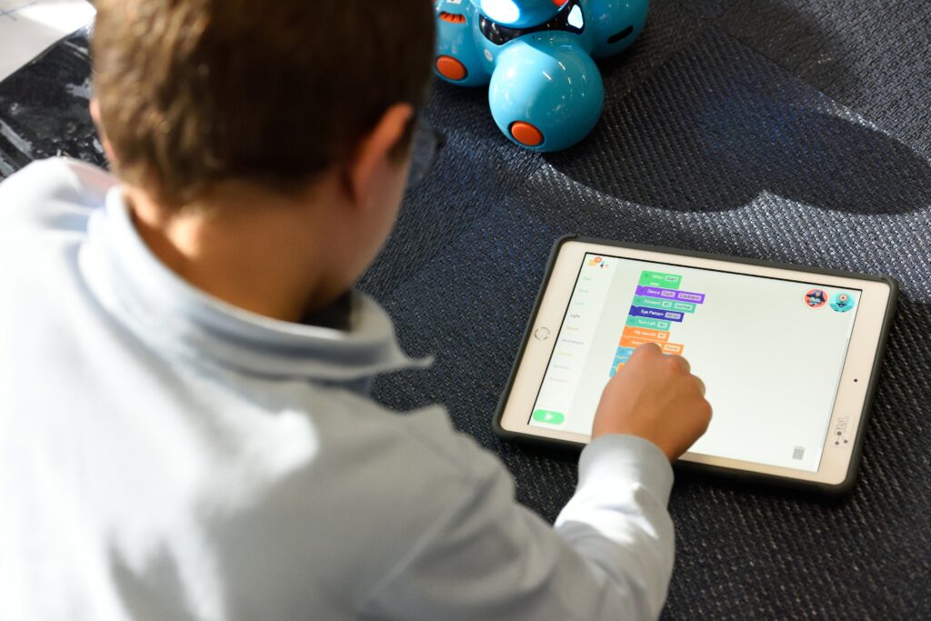 Looking over the shoulder of a child who is using an iPad to play an education game.